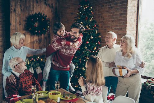 Multi-generational family gathered together in front of holiday decorations