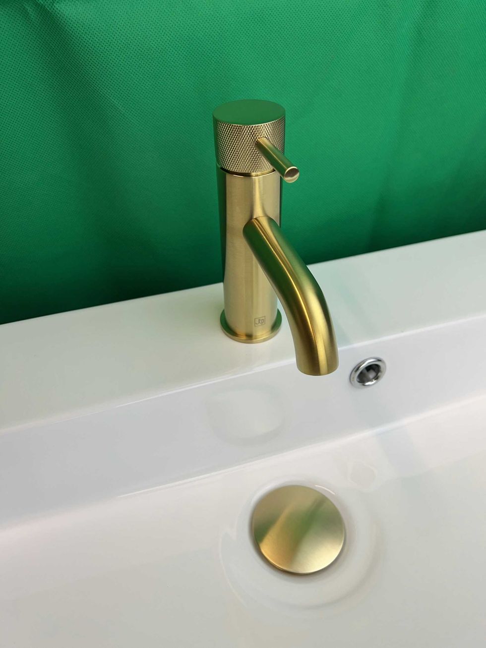 a bathroom sink with a gold faucet and a green background