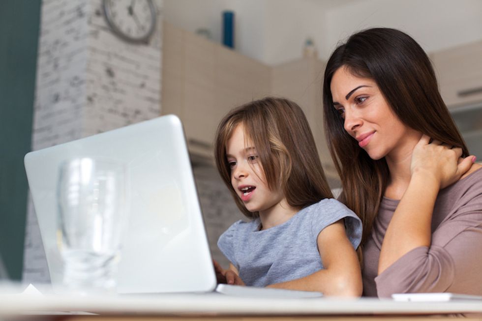 A child and a female figure seated in front of a laptop, viewing something on the screen with interest