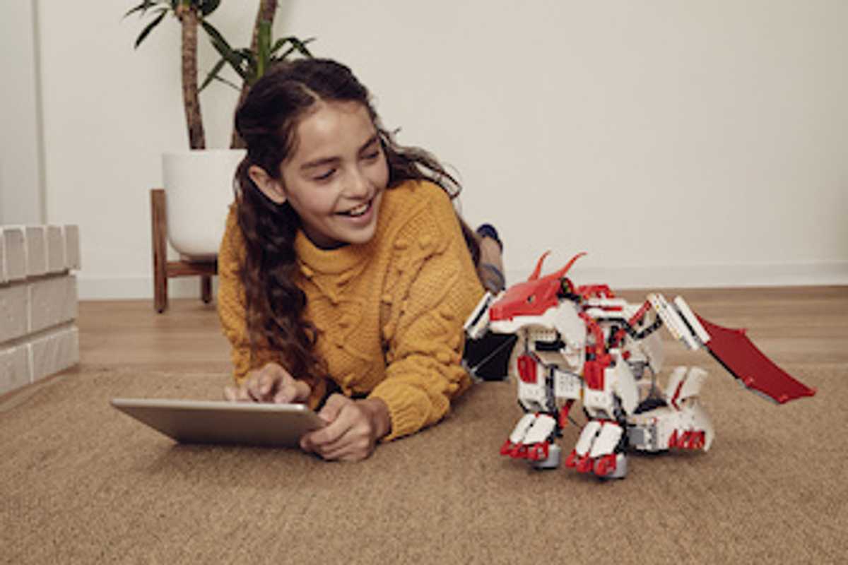 A child sitting on the ground next to UBTECH Jimu FireBot Kit, a build your own robot dragon