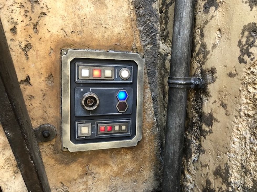 A control panel with red, blue and orange lights that are square, round and hexagonal shaped.