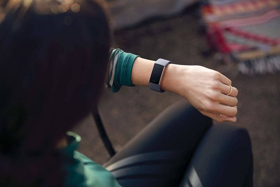 A Fitbit Charge 3 in dark gray being worn on someone's arm