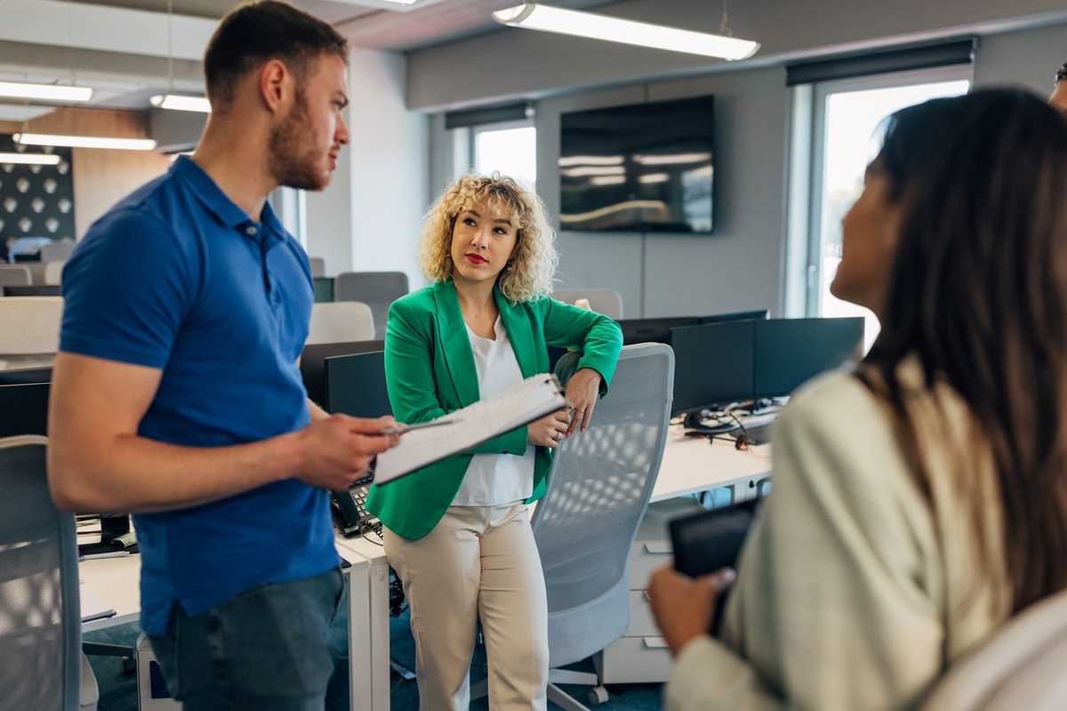A group of co-workers are discussing a business project they are working on as a team. They stand in the meeting room and agree on the implementation of the business strategy stock photo
