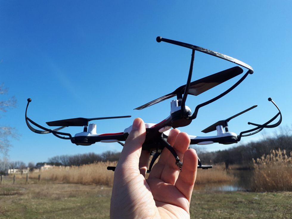 A hand holding a small consumer drone