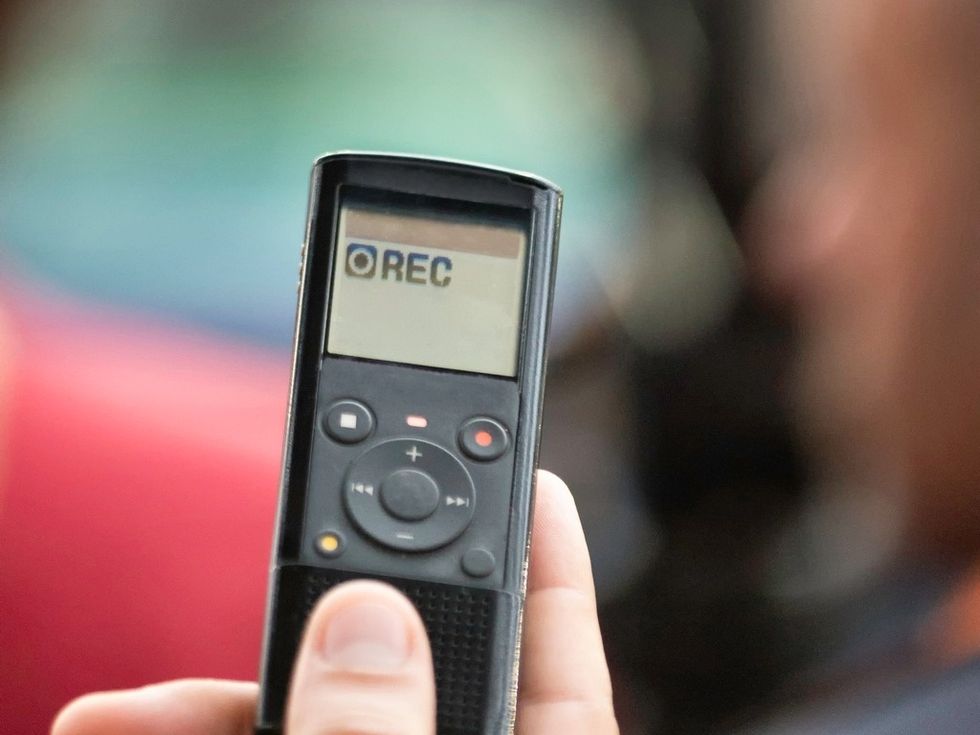 A hand holding a small digital recording device