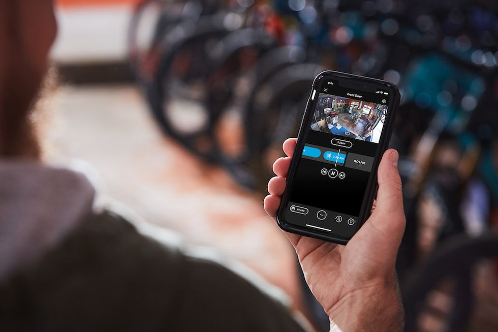 A hand holding a smartphone and viewing a camera view of a room