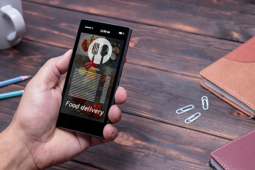 A hand holding a smartphone with the words 'food delivery' on the screen