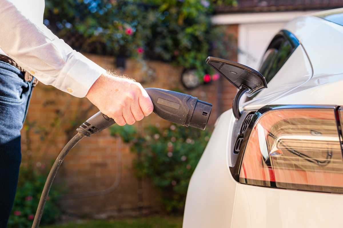 a man charging his electric car at home.