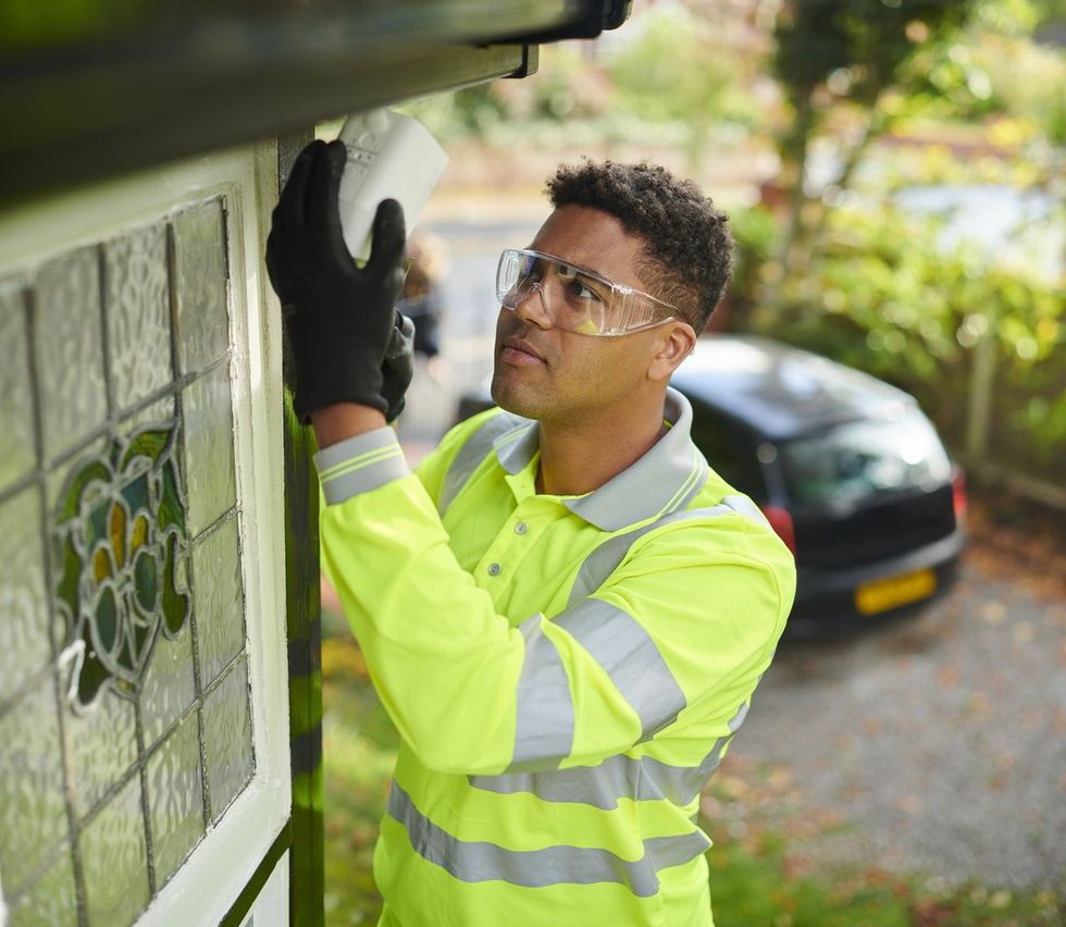 a man installiing an outside security camera on a house