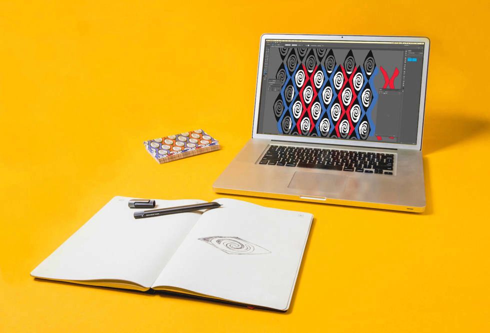 A Moleskine notebook on a yellow background, with a laptop computer in the background
