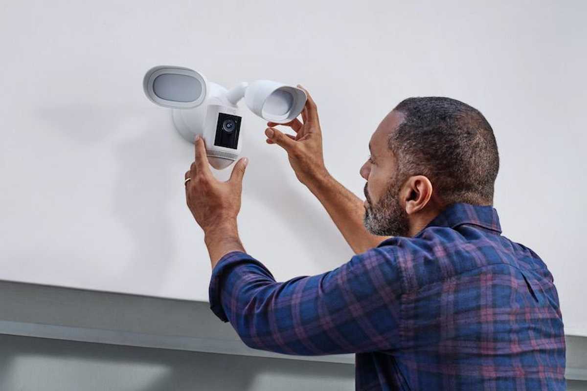 a person installing a Ring Floodlight Cam Wired Pro on a garage