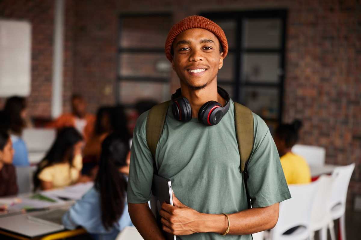 A photo of a college student wearing headphones and carrying a laptop