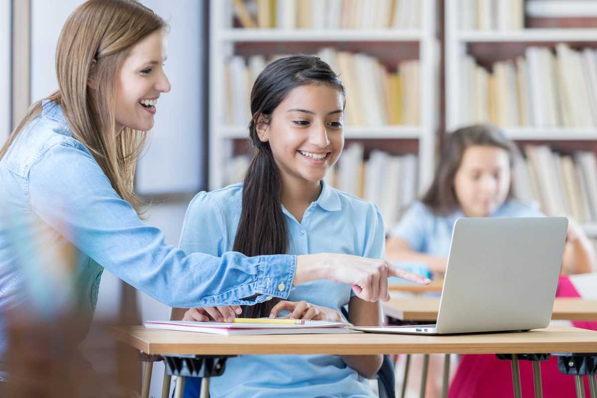 a photo of a female teacher teaching students math on a computer