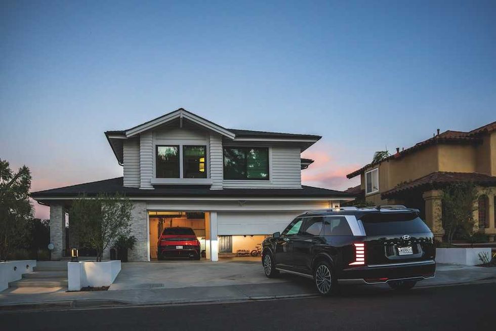 a photo of a Hyundai pullng up to a house and their garage door is opening.