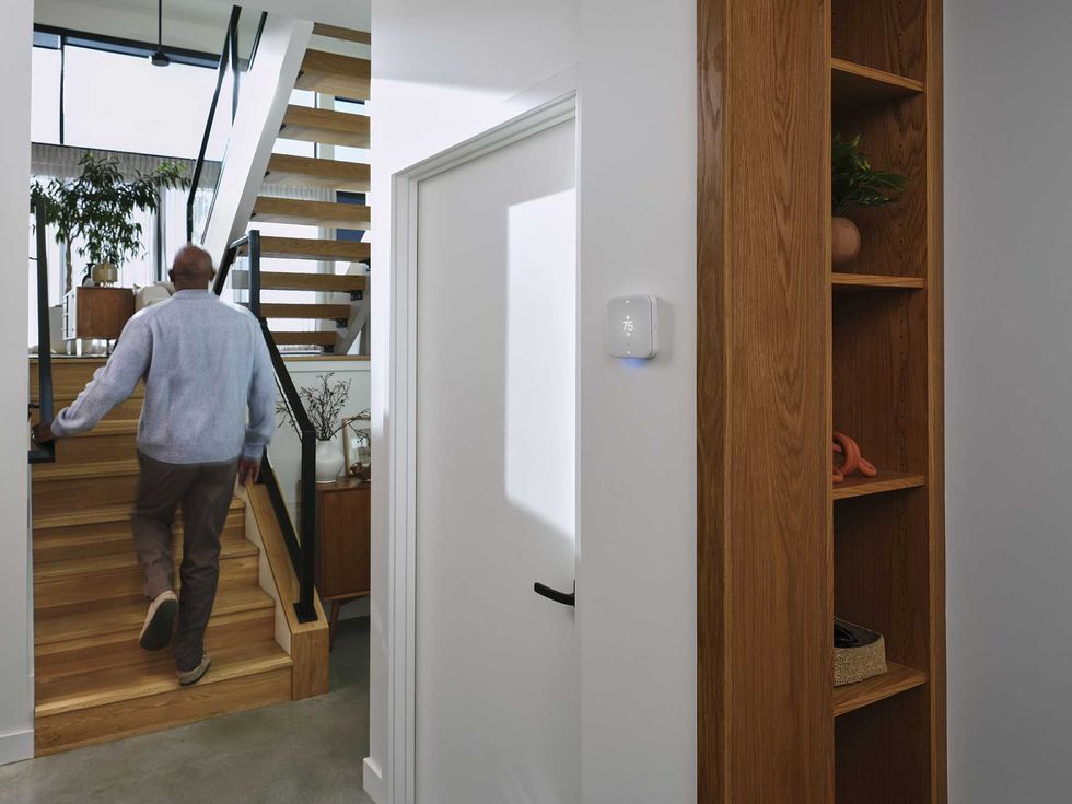 a photo of a man in a hallway with Vivint thermostat on the wall