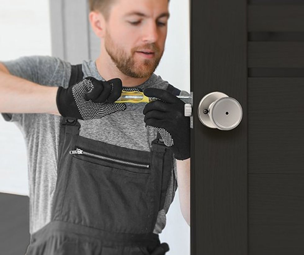 a photo of a man installing a Kwikset Maven door knob on a door