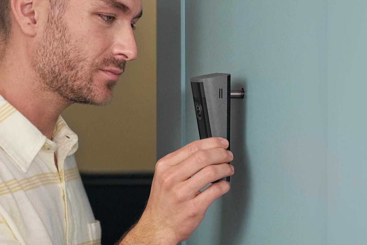 a photo of a man installing Ring Peephole Cam 2K