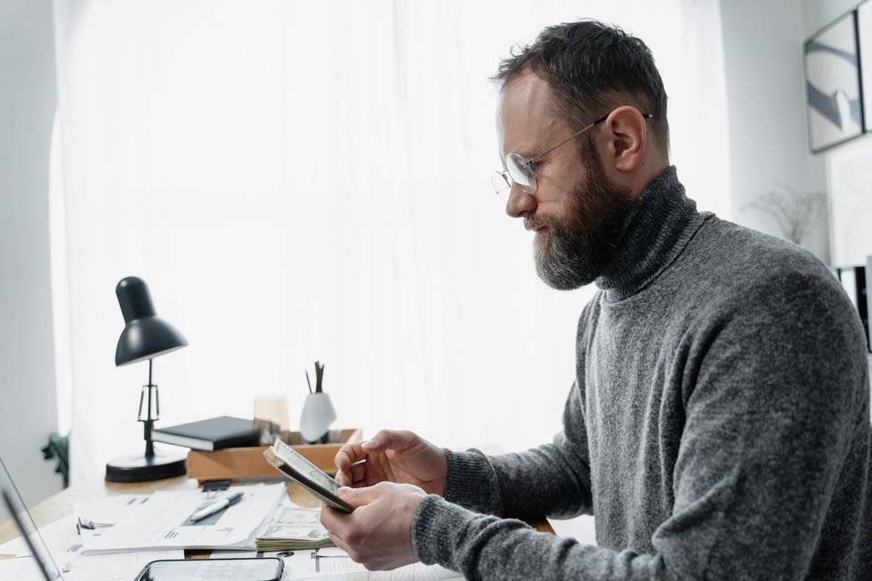 A photo of a man working at a desk on his smartphone