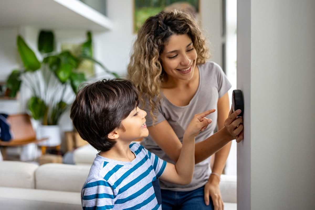 a photo of a mother and son using a smart theremostat