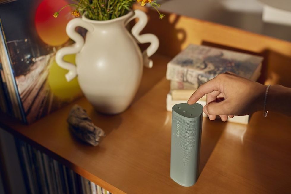 a photo of a person touching the top controls of Sonos Roam 2 Portable Wireless Speaker