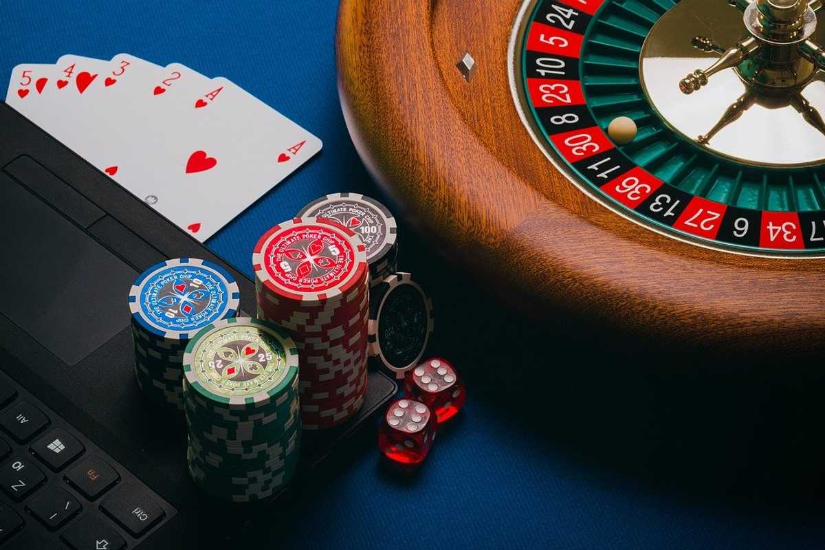 a photo of a roulette wheel, chips, cards, dice and a keyboard