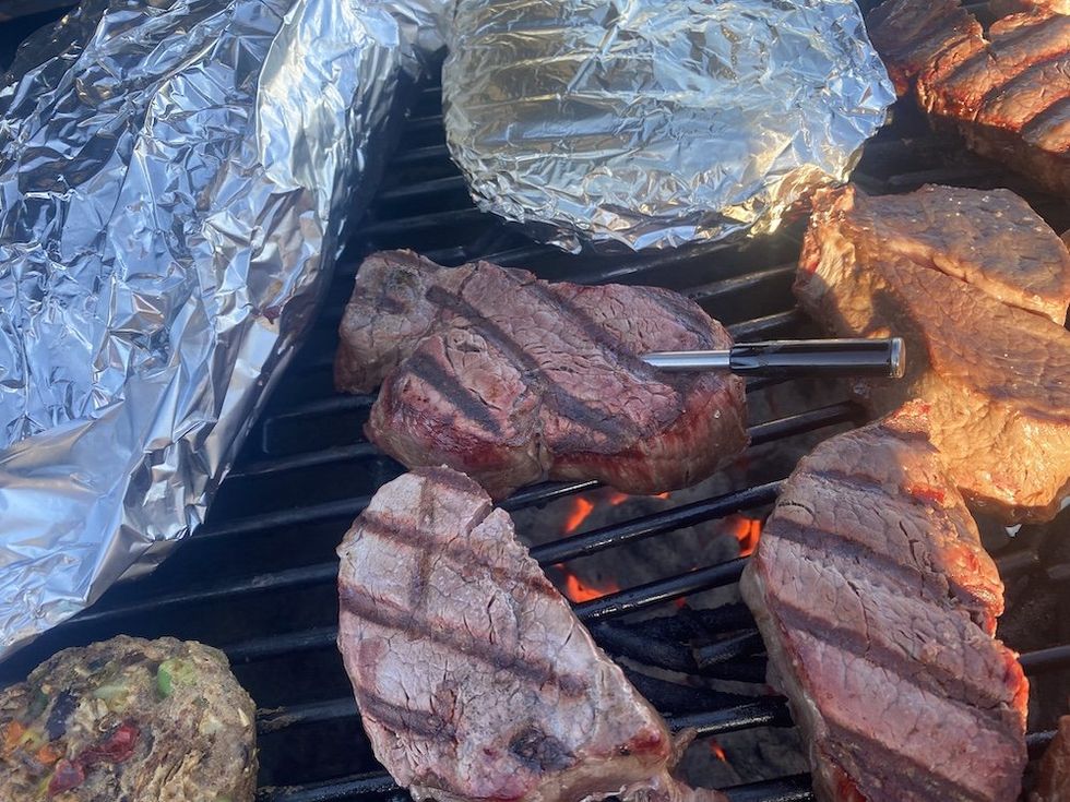 a photo of a smart meat thermometer inserted in a steak on a grill