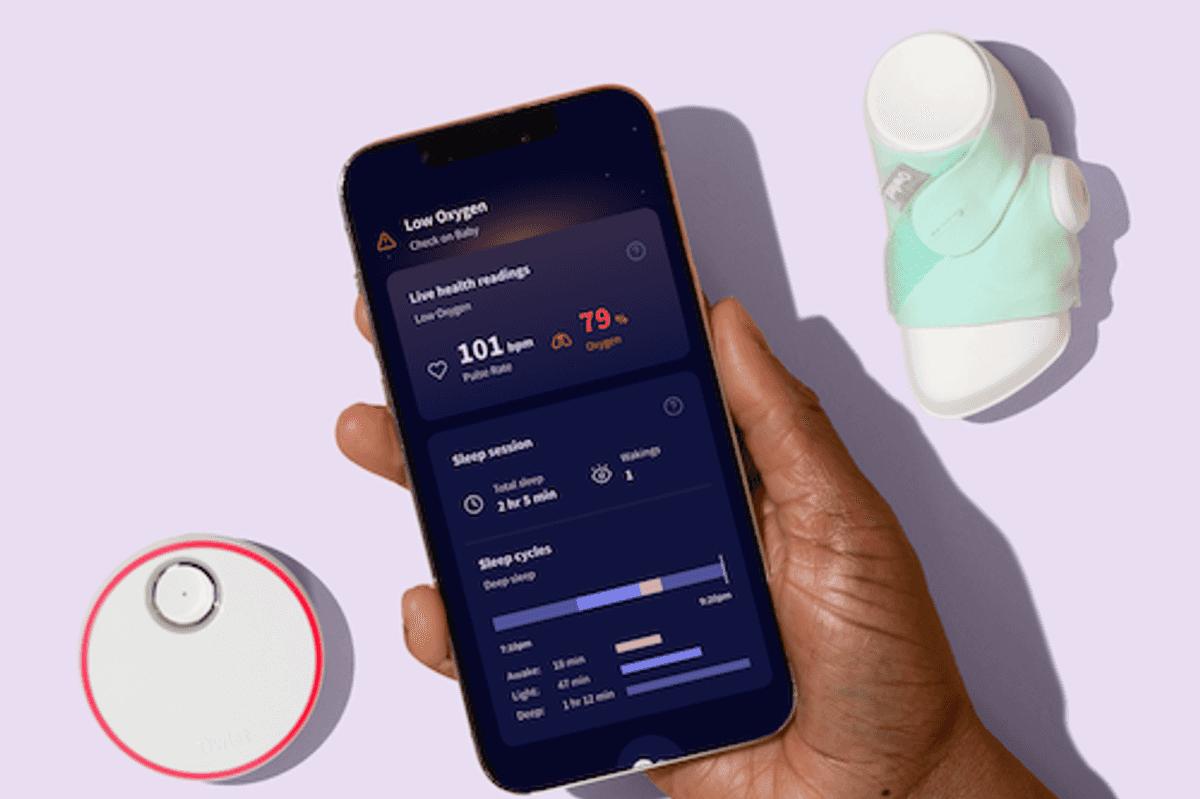 a photo of a smartphone showiing the Owlet app with the Owlet Dream sock and hub