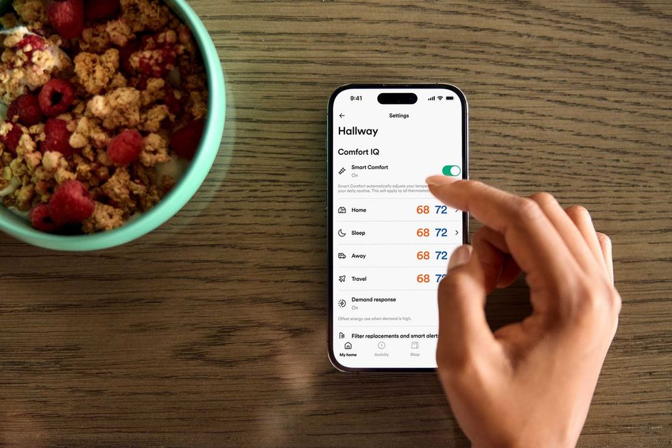 a photo of a smartphone showing Vivint app for Comfort IQ