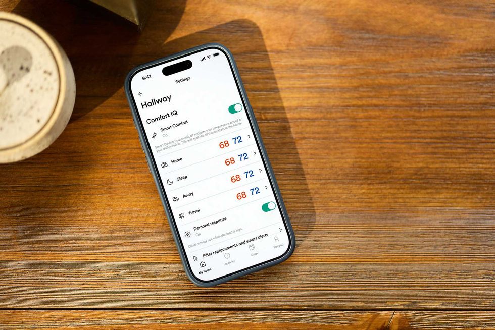 a photo of a smartphone showing Vivint app for Comfort IQ