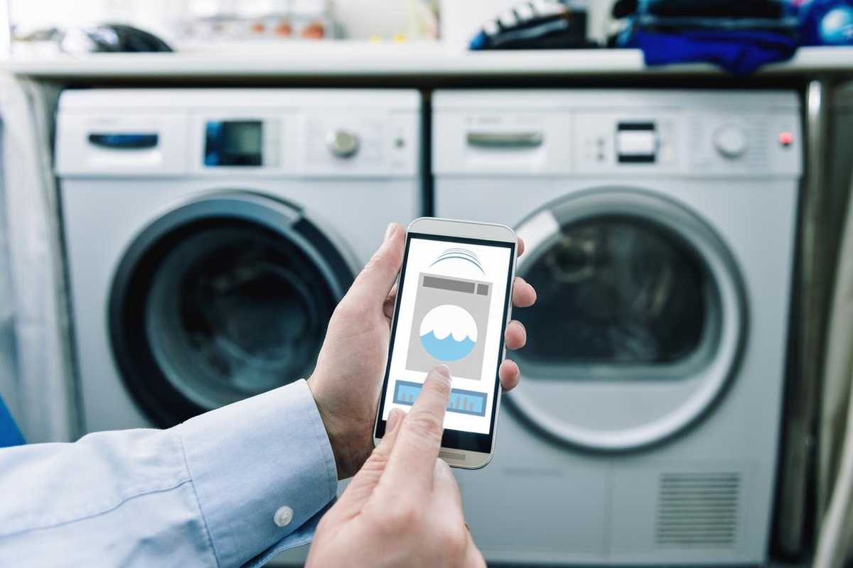 a photo of a smartphone with app controlling washing machine and dryer.