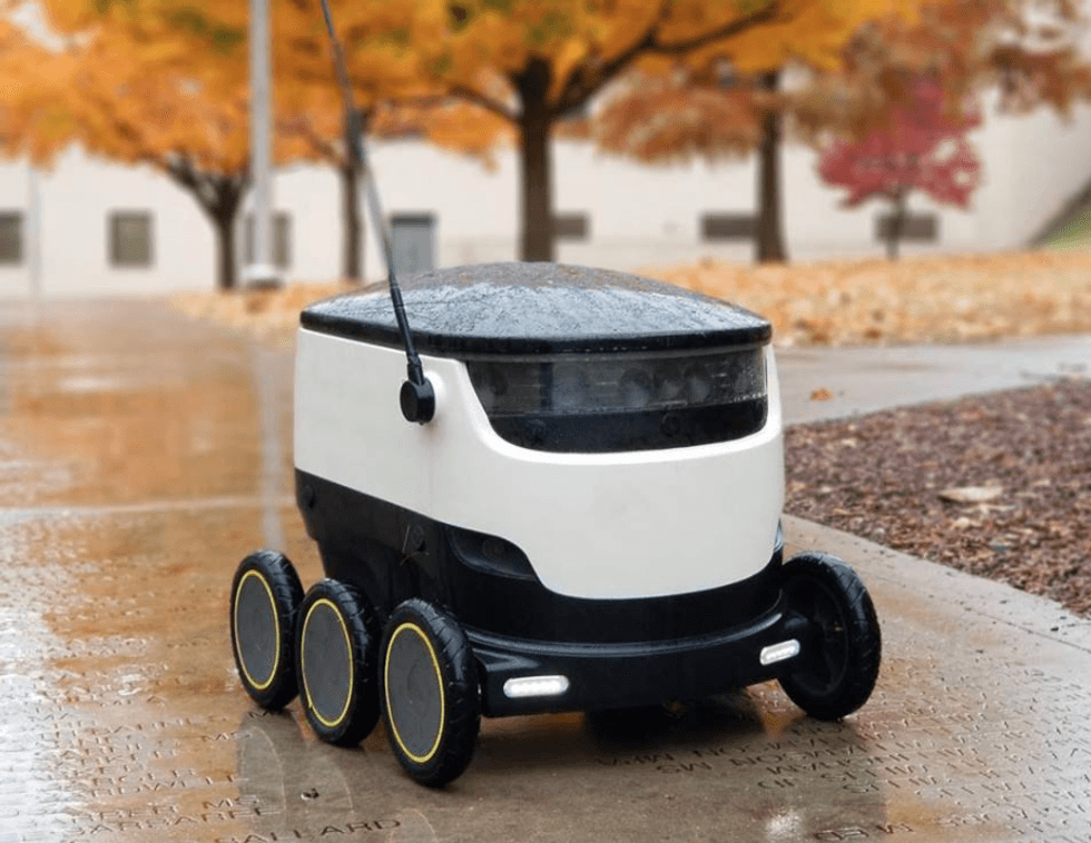 A photo of a Starship autonomous robot in the rain, making a delivery