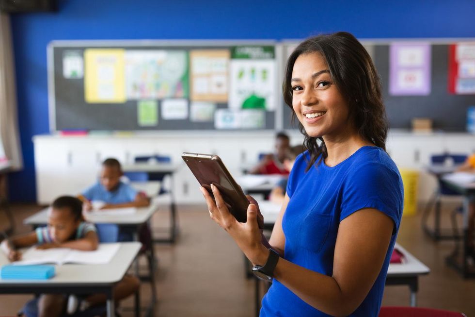 a photo of a teacher using a tablet to teach students in a classroom