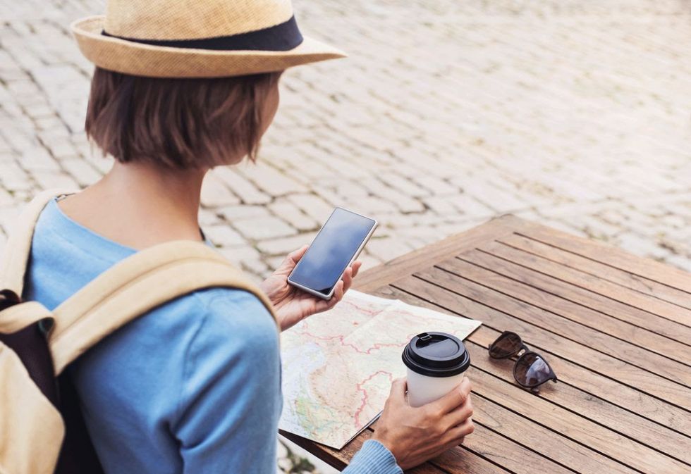 A photo of a traveler using a mobile device while traveling with a map visible