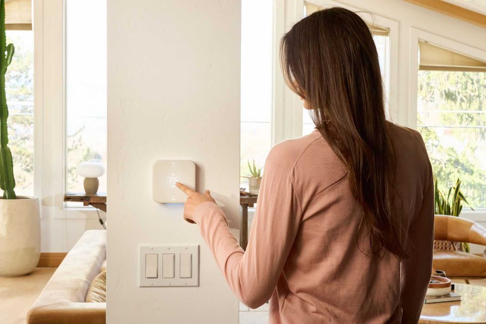 a photo of a woman controlling a Vivint thermostat