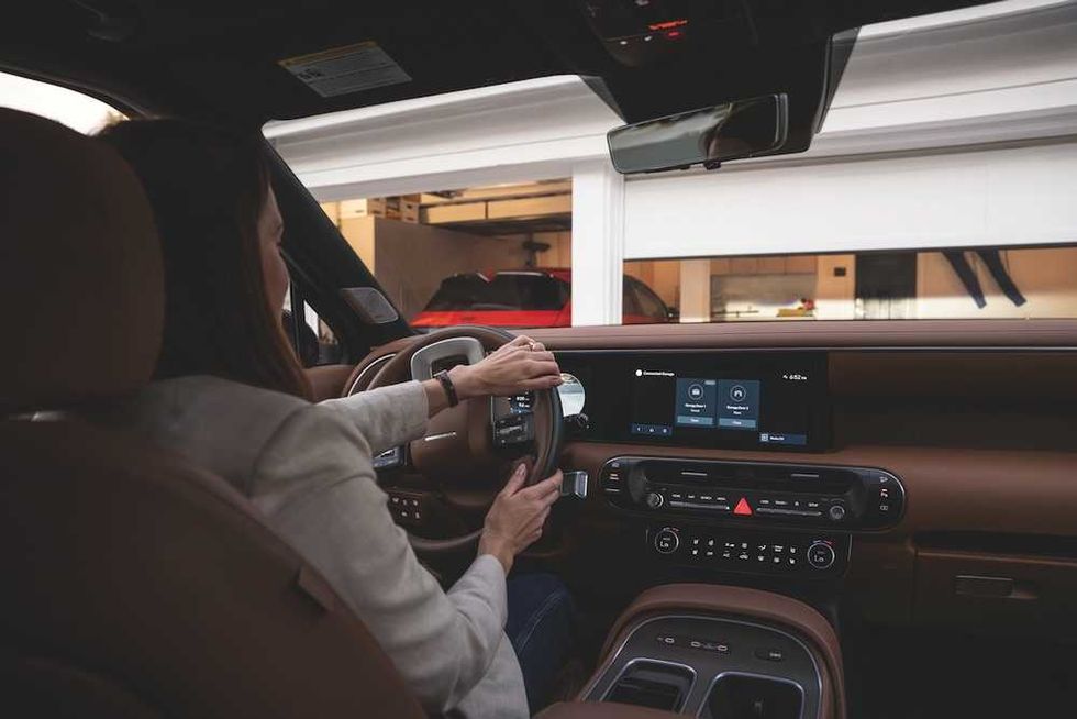 a photo of a woman driving up to her garage as her  Hyundai myQ Connected Garage opens her garage door