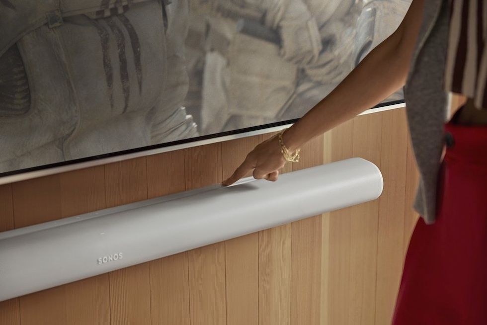 a photo of a woman touching the Sonos Arc Ultra soundbar controls