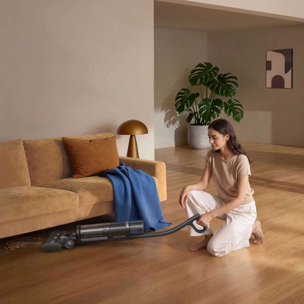 a photo of a woman vacuuming underneath a couch with Roomba Electro Plus