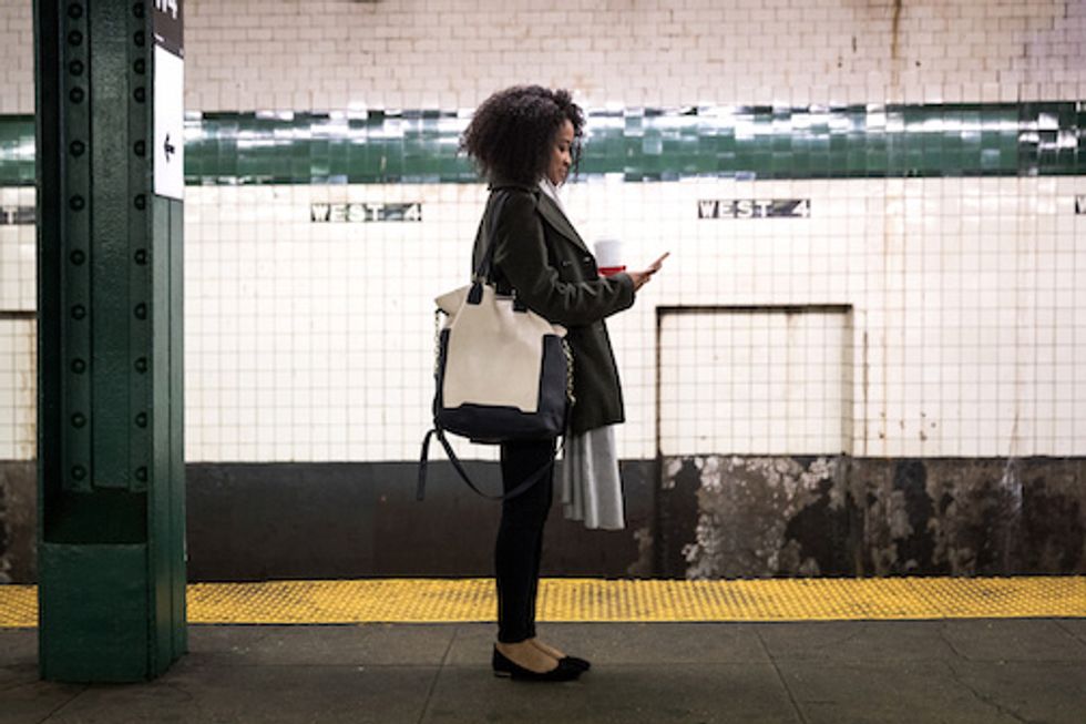 A photo of a woman waiting for a subway in New York City
