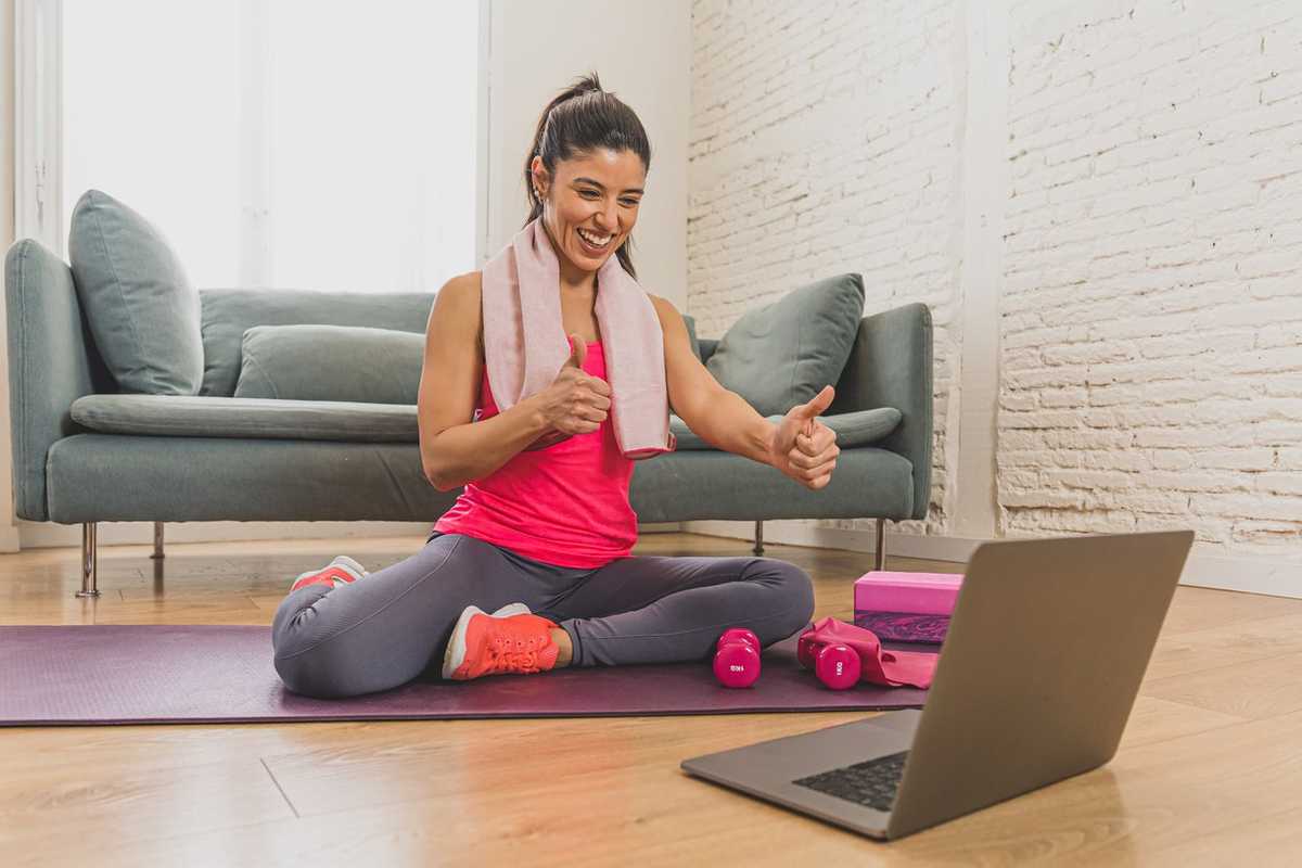 a photo of a woman working out with a virtual personal trainer on her laptop