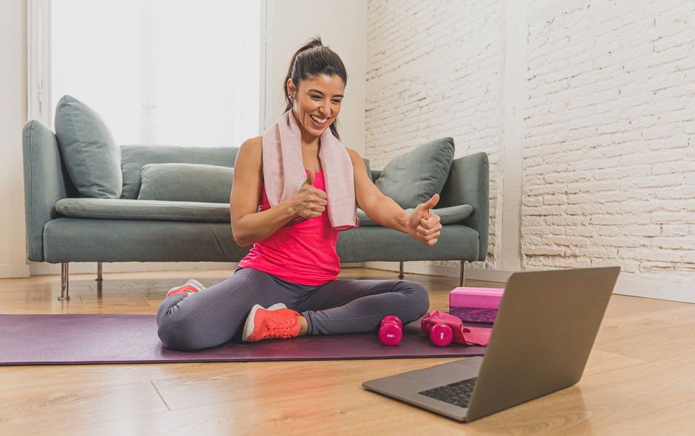 a photo of a woman working out with a virtual personal trainer on her laptop