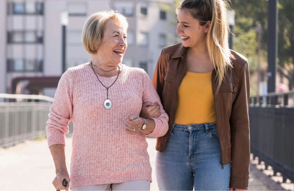 a photo of a young woman walking with a elderly woman wearing an ADT medical alert pendant