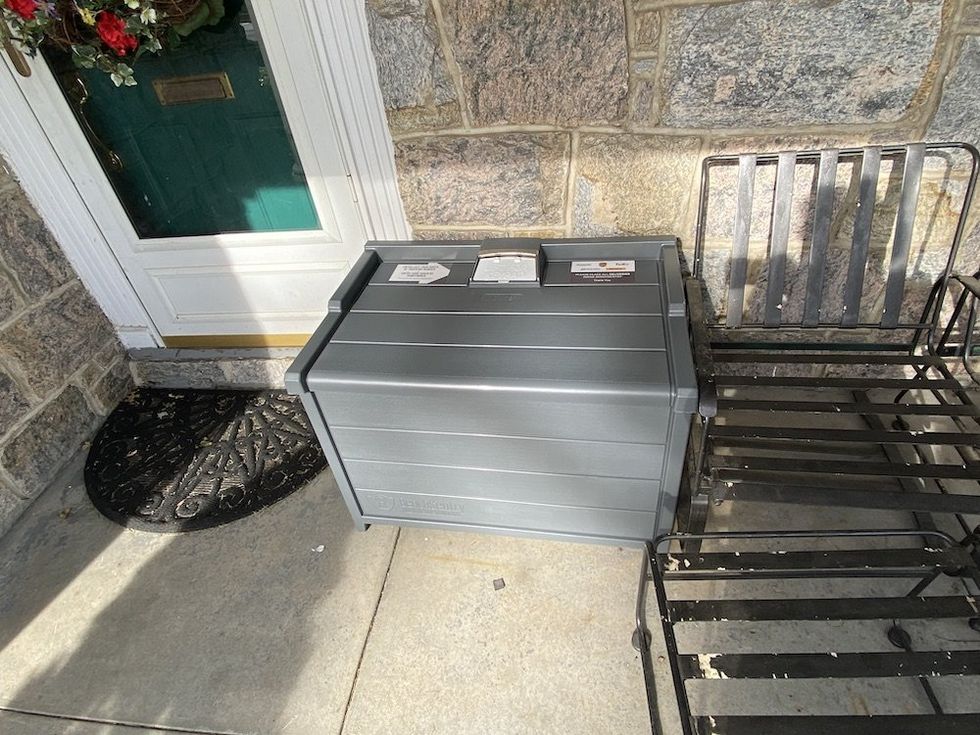 a photo of BenchSentry by Genie Secure Package Delivery box on a porch next to a chair