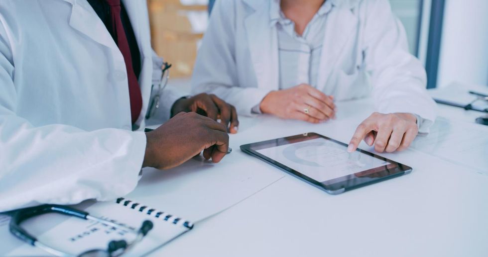 a photo of doctors reviewing patient data on a tablet