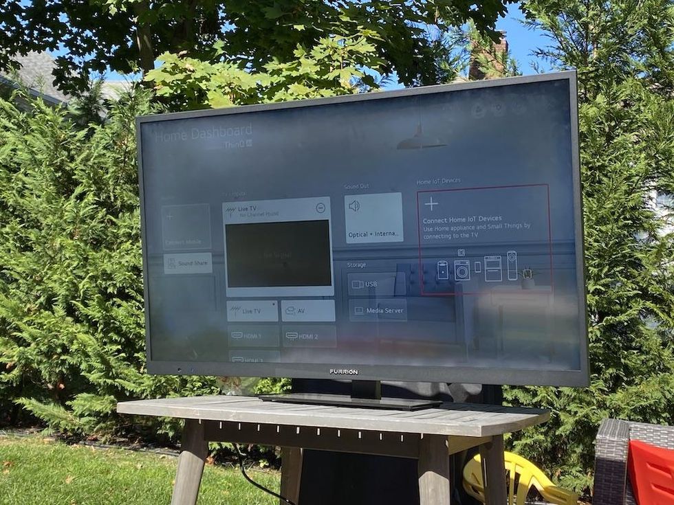 a photo of Furrion Aurora Smart Outdoor TV in full sunlight ina yard