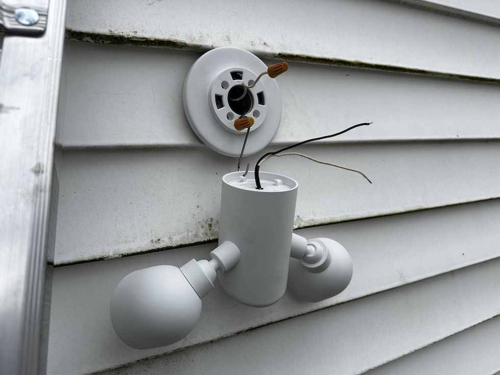 a photo of Google Nest Cam with Floodlight hanging on the S hook from the mounting bracket