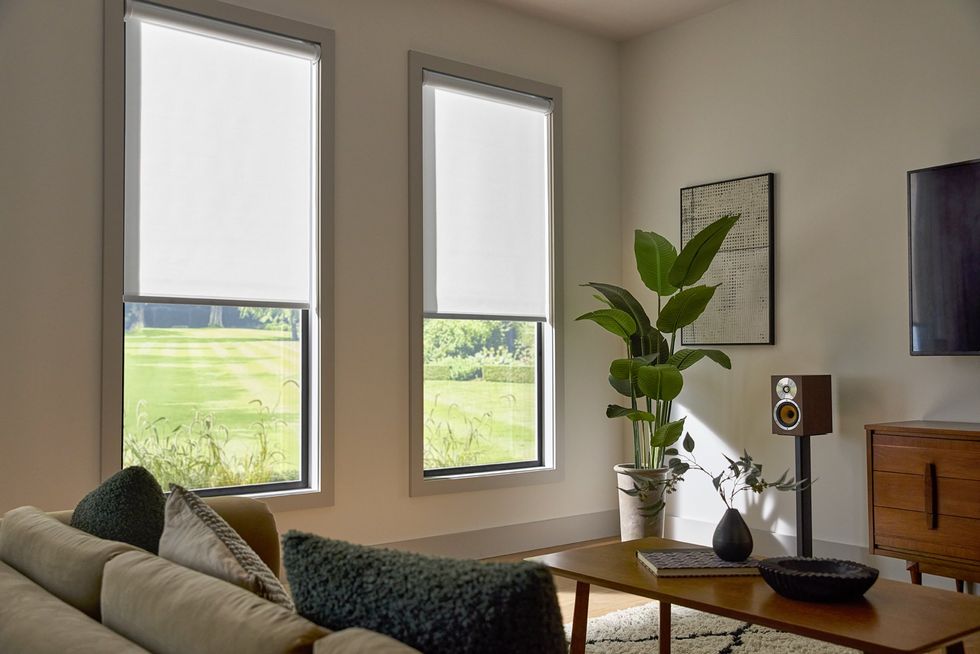 A photo of Lutron Caseta Smart Roller shades on windows in a den.