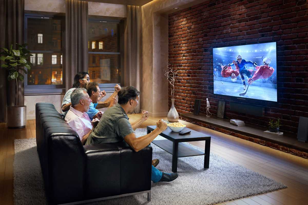 a photo of men watching a sporting event while sitting on a couch