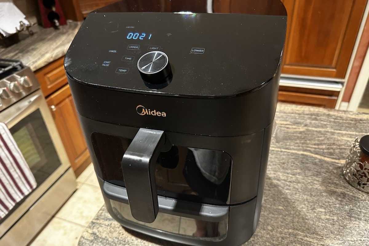 a photo of Midea Two-Zone 11QT Air Fryer Oven cooking on a countertop in a kitchen