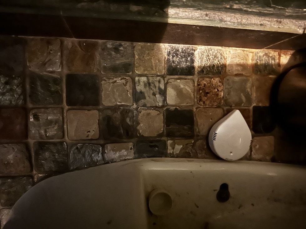 a photo of Moen Smart Leak Detector installed on the floor next to a toilet