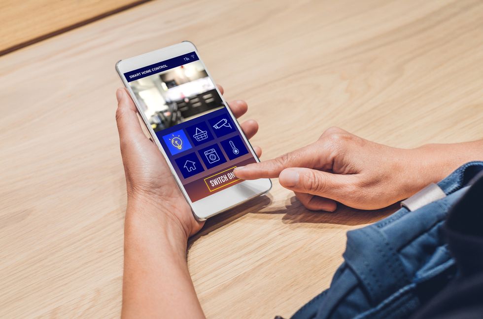 A photo of someone using a smartphone to control their smart home features